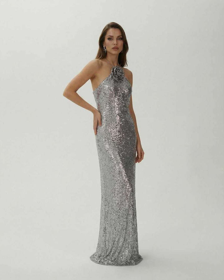 Atractivo vestido maxi de noche con lentejuelas plateadas y escote halter. Look glamoroso para cualquier evento de gala.