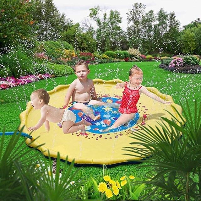 Niños riendo alrededor de una fuente de agua en el jardín, disfrutando de diversión acuática al aire libre.