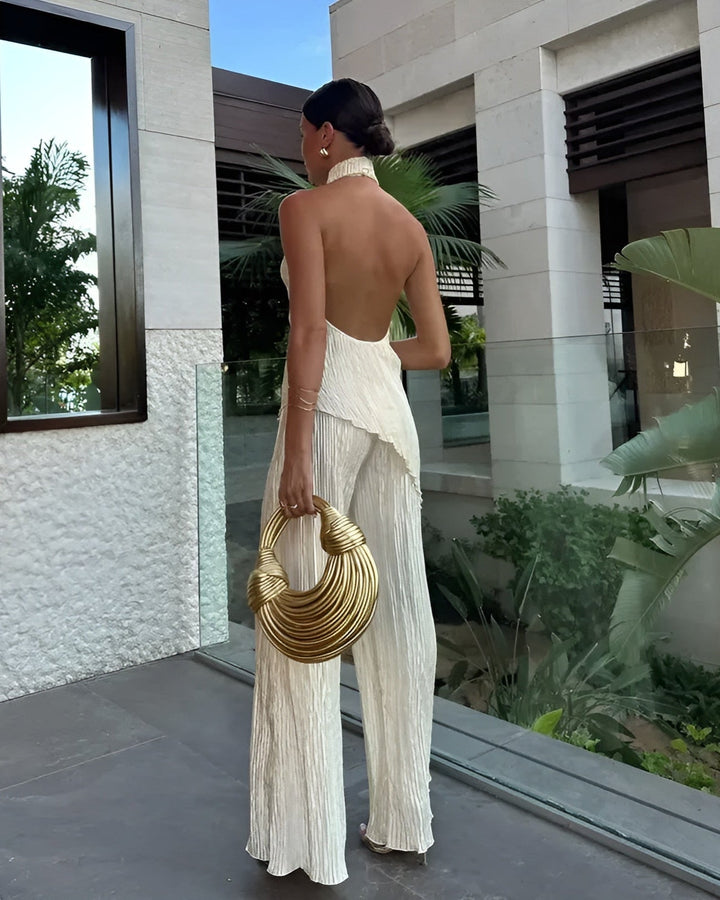 Modelo de mono beige para mujer, elegante y cómodo, con cuello halter, pierna ancha y detalles plisados.