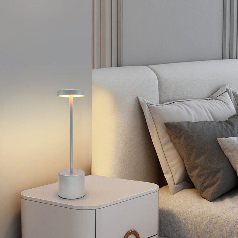 Primer plano de lámpara de mesa LED moderna, acabado elegante y base recargable sin cable.