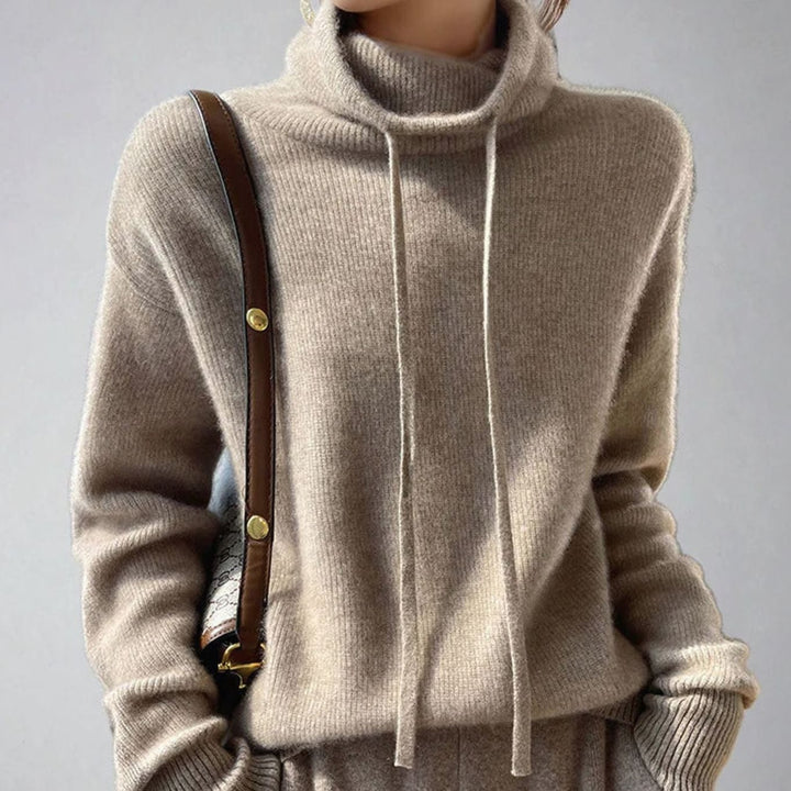 Jersey rosapastel de punto holgado con cuello alto y cordón para mujer, estilo moderno y casual.