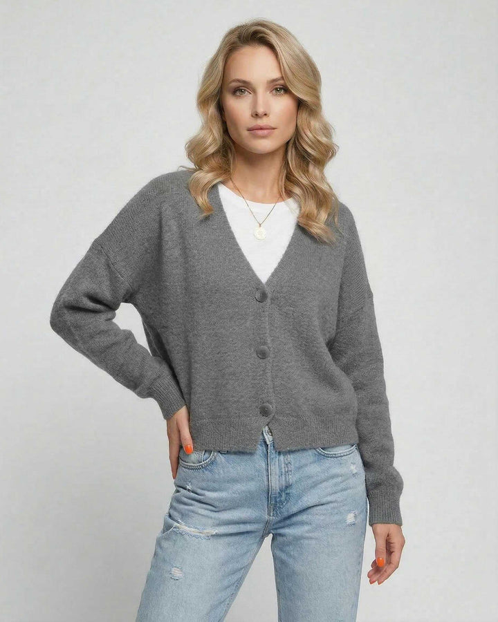 Mujer vistiendo cárdigan gris clásico, mostrando su suavidad y estilo para ropa de entretiempo.