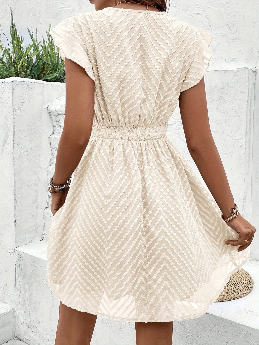 Vestido de dama corto, bordado floral, con cuello en V y cintura entallada. Estilo chic para fiesta.