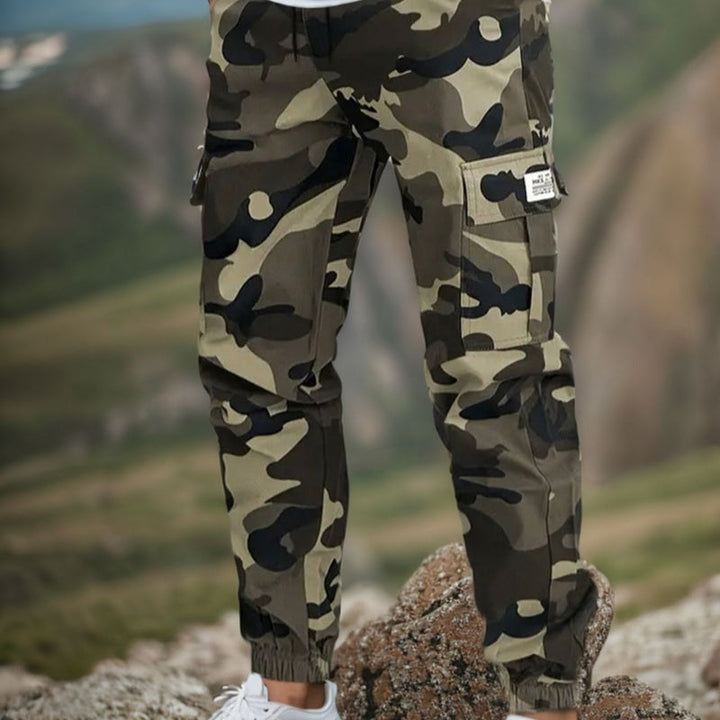 Hombre vistiendo pantalones de camuflaje ajustados, ideales para un look urbano y casual diario.
