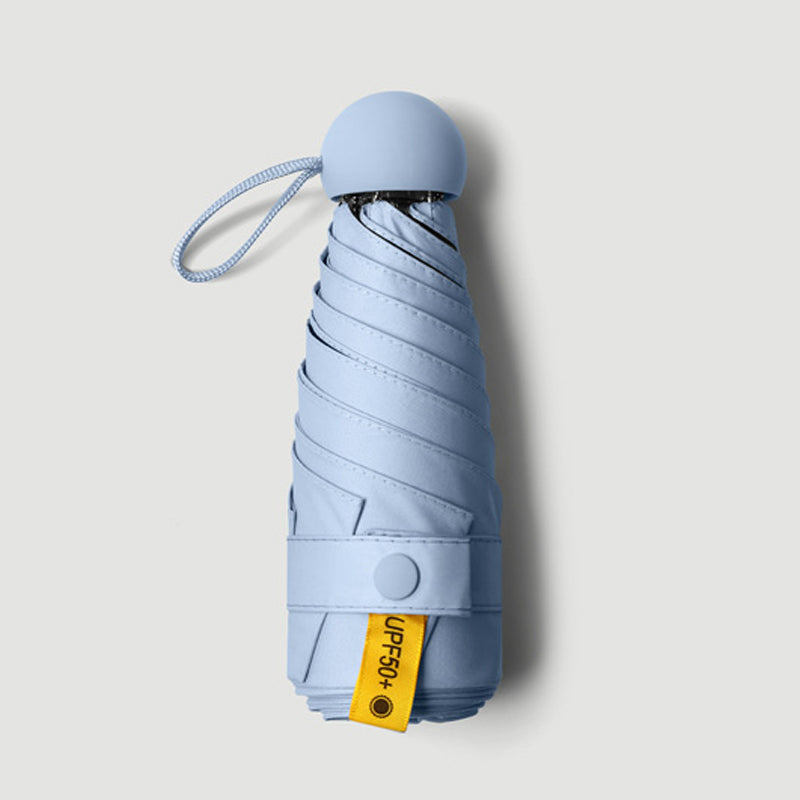 Paraguas de bolsillo cerrado, diseño compacto de cápsula, listo para protegerte de lluvia y sol en viaje.