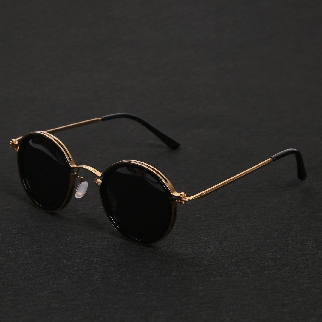 Primer plano: gafas de sol negras de montura redonda y varillas doradas. Lentes polarizadas, protección UV400. Estilo unisex.
