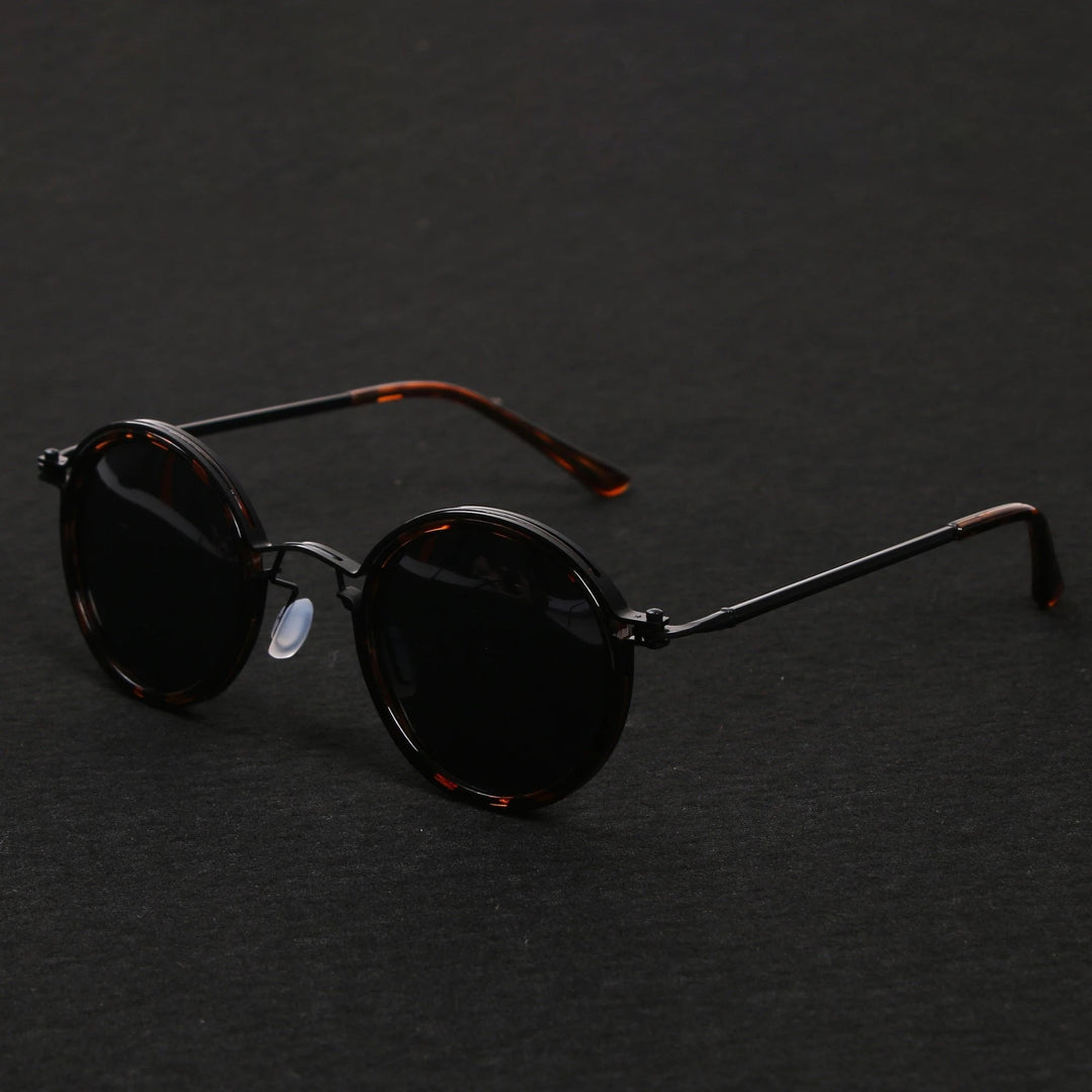Vista lateral de gafas de sol unisex con montura redonda negra y varillas doradas. Lentes polarizadas UV400.