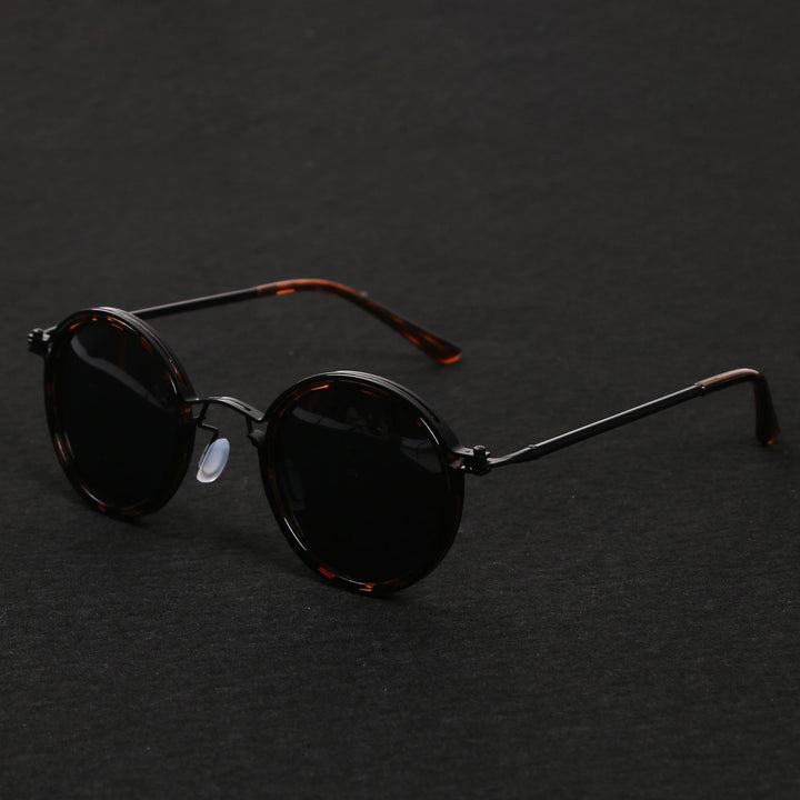 Vista lateral de gafas de sol unisex con montura redonda negra y varillas doradas. Lentes polarizadas UV400.