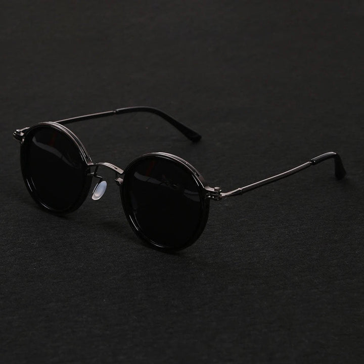 Gafas de sol polarizadas para exterior. Montura redonda negra, varillas doradas. Protección UV400, visión clara y confort.