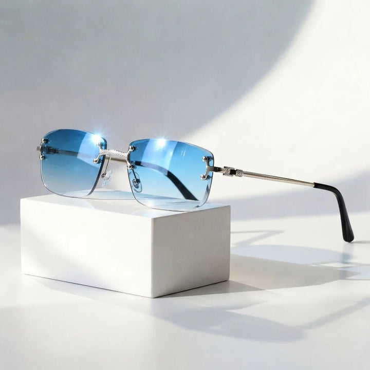 Gafas de sol grises unisex sin montura, con lentes degradados y protección UV400. Varillas doradas.