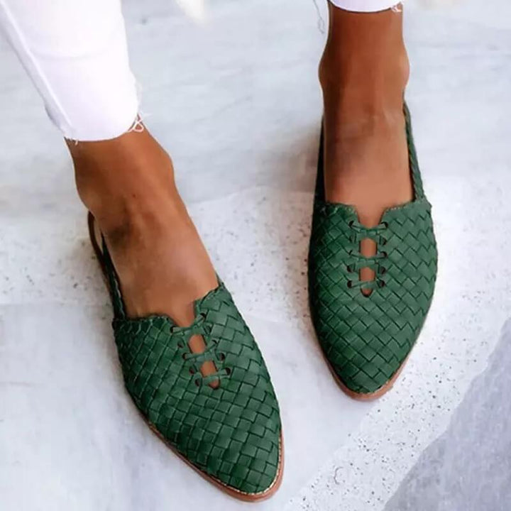Mujer usando sandalias planas trenzadas artesanales, perfectas para un estilo de verano cómodo y fresco.