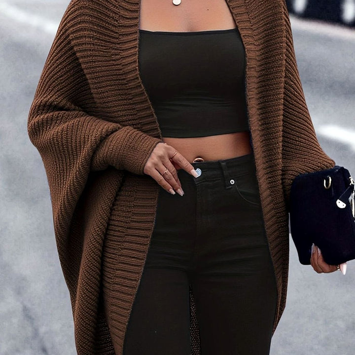 Mujer posando con cárdigan de punto oversize largo y abierto, moda casual de otoño.