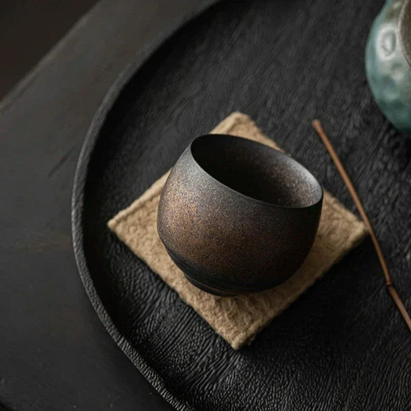 Taza redonda de gres, artesanal y sin asa, perfecta para café o té en el hogar.