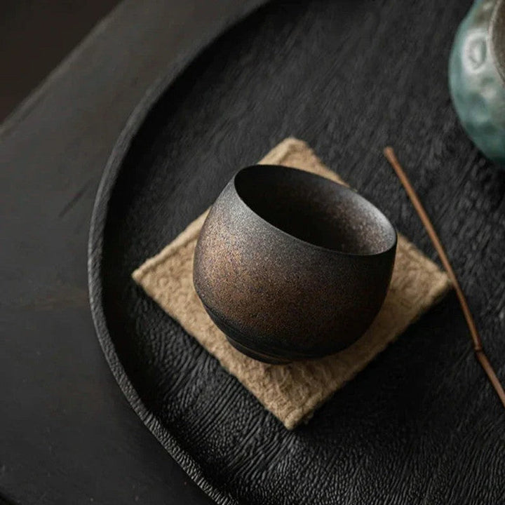 Taza redonda de gres, artesanal y sin asa, perfecta para café o té en el hogar.