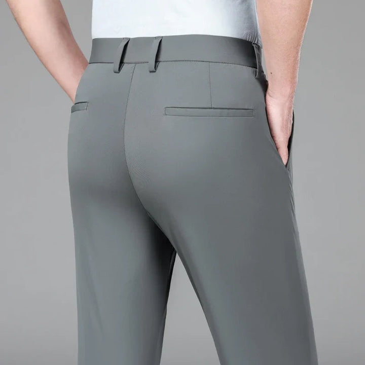 Hombre posando con pantalón chino slim elástico, resaltando el ajuste moderno y la comodidad.
