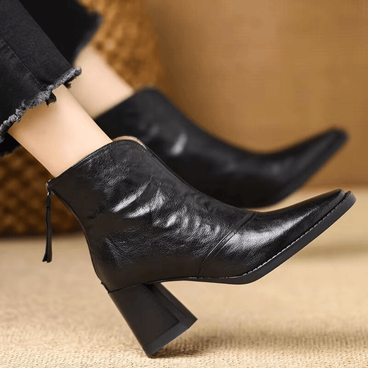 Par de botas de mujer estilo tobillo con tacón ancho. Diseño urbano moderno y cremallera elegante.