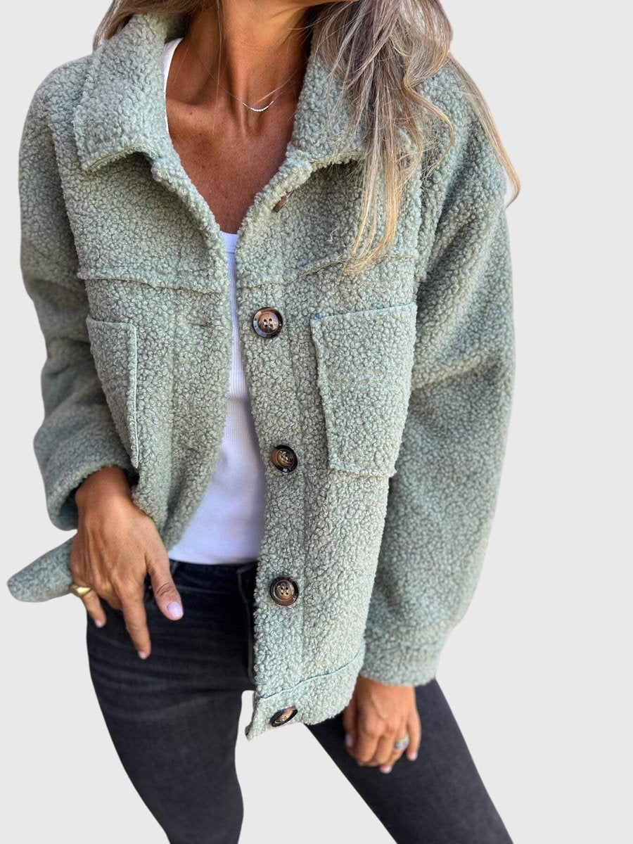 Mujer vistiendo chaqueta de borreguito con botones y cuello amplio. Abrigo cálido, estilo elegante y casual para invierno.