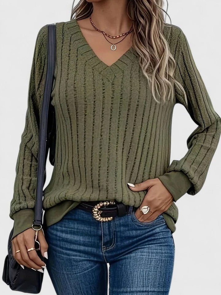 Vista detallada del punto trenzado en suéter de mujer con escote en V. Jersey de moda para temporada fría.