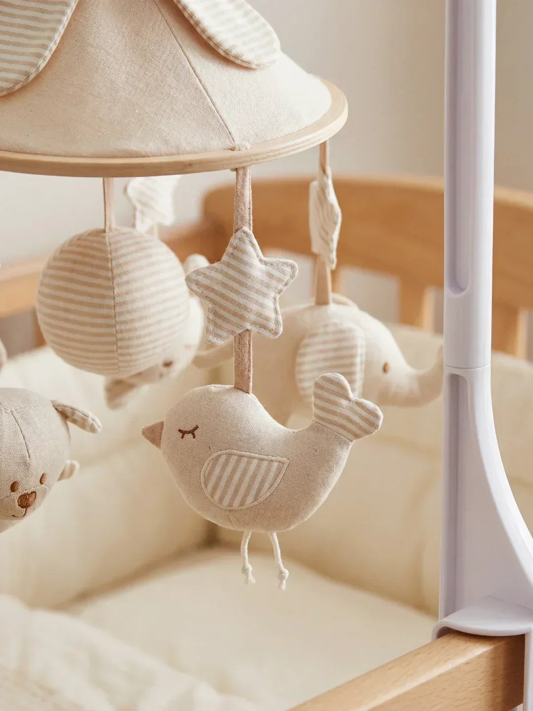 Detalle del móvil de cuna de madera: figuras animales colgantes y mecanismo musical suave.